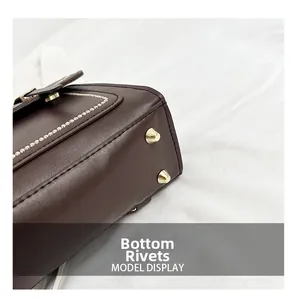 Detail of dark brown leather bag base showing golden metal feet and white stitching