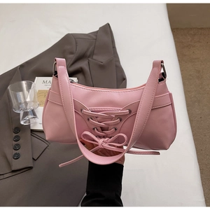 Détail du sac baguette rose avec lacets, nœud et texture en cuir premium