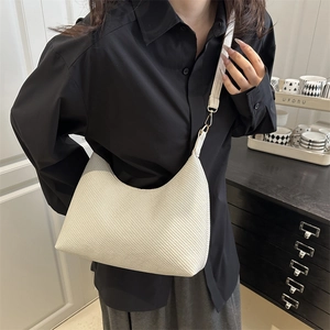 Minimalist white woven hobo bag with gold hardware shown on a model in a casual setting