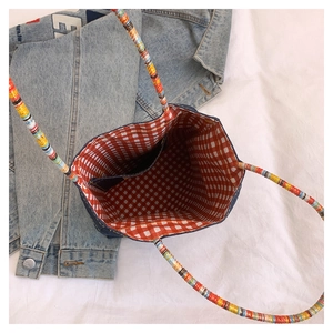 Detail showing the red checkered lining and woven handle of the denim tote bag
