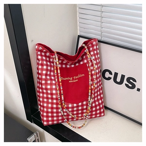 Détail du cabas en toile à carreaux rouges avec anses perlées et poche avant