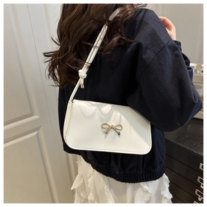 Détail d'un sac à bandoulière en similicuir blanc avec nœud en métal et bandoulière