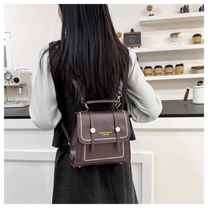 Detail of dark brown retro leather backpack with white stitching and gold metal accents