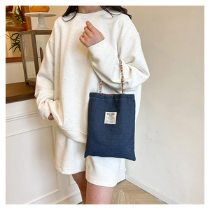 Detail of a blue denim tote bag with ethnic woven straps and Duo Ning Bag textile label