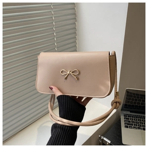 Detail of beige leather small square bag with golden bow buckle and slim shoulder strap