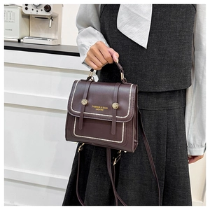 Detail view of dark brown leather handbag with pearl edge trim and golden buckle accents