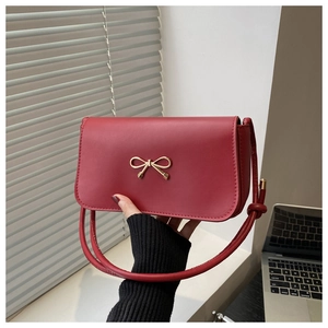 Detailed close-up of a red leather crossbody bag with an elegant golden bow buckle