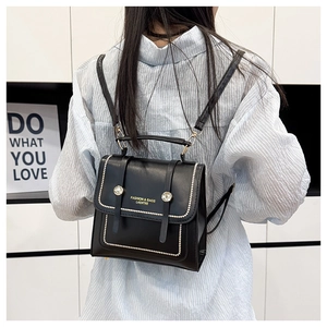 Detail of black faux leather backpack featuring pearl trim and gold brand logo on back