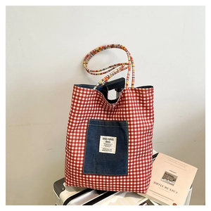 Detail of red gingham tote bag featuring a denim pocket and colorful woven rope handles