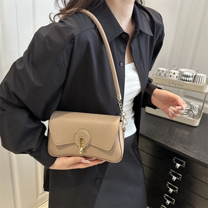 Elegant khaki shoulder bag with round gold buckle shown on a model in a minimalist setting