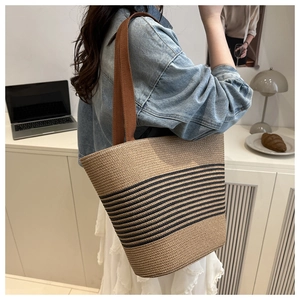 Close-up of a woven tote bag with black stripes being worn by a model in an office setting