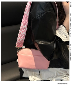 Detail of pink leather crossbody bag featuring stylish patterned woven wide shoulder strap