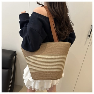 Detail of a large woven straw tote bag with brown straps in a summer lifestyle setting