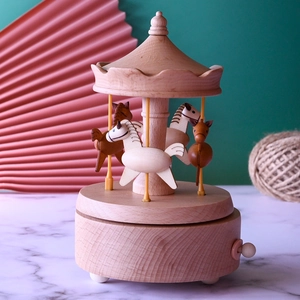 Detail view of a handcrafted wooden carousel music box with mechanical winding lever