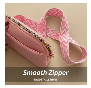 Detailed close-up of pink crossbody bag featuring gold zipper and woven patterned strap