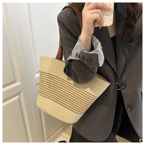 Close-up of beige and brown striped straw tote bag with brown fabric shoulder straps