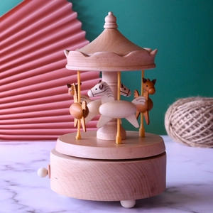 Handcrafted wooden carousel music box with rotating horses and natural grain finish