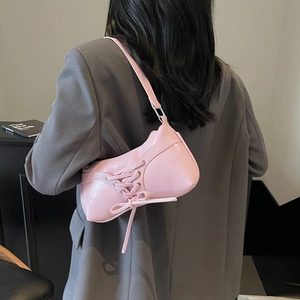 Pink underarm shoulder bag with lace-up design worn on grey suit blazer