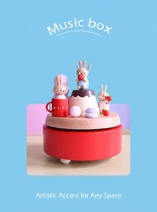 Close-up of a handmade wooden music box with painted rabbit and miniature dessert details