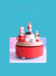 Close-up of a handmade wooden music box with painted rabbit and miniature dessert details