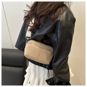 Détail du sac bandoulière beige avec large sangle d'épaule à motif chevron noir et blanc