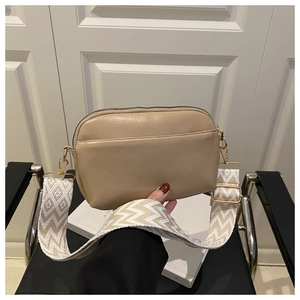 Detail of khaki crossbody bag with wide geometric woven strap and golden metal hooks