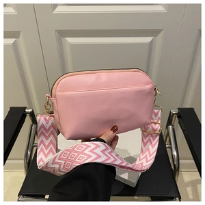 Detail of pink crossbody bag with wide jacquard shoulder strap and gold hardware