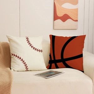 Sportliche Dekokissen mit Baseball- und Basketball-Print auf einem beigen Sofa