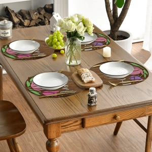 Detail of round linen placemats with tulip floral patterns on a wooden dining table