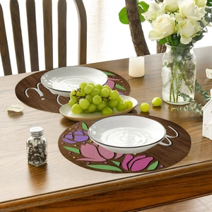 Detail of round linen placemats with floral tulip print and letter W on a wooden table