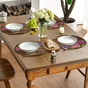 Detailed view of round floral linen placemats set on a rustic dark wood dining table