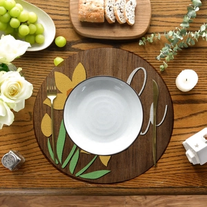 Detailed top view of a round floral placemat with sunflower motifs on a wooden table