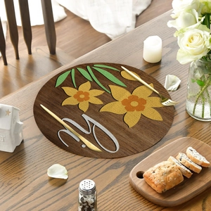 Detail of round linen placemat with yellow floral pattern and wood grain texture on a table
