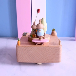 Mechanical wooden music box featuring cute rabbits and carrots on light wood base