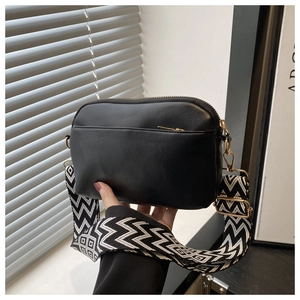 Detail of black crossbody bag featuring gold-tone hardware and chic geometric strap