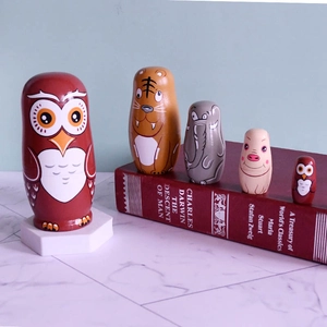 Detail of five-piece wooden owl nesting dolls displayed on a book and marble surface