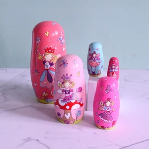 Detailed view of 5-piece pink fairy wooden Russian nesting dolls on marble surface