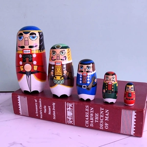 Set of 5 wooden nutcracker soldier nesting dolls displayed on classic books
