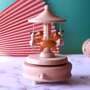 Handcrafted wooden carousel music box with rotating horses on a minimalist marble surface