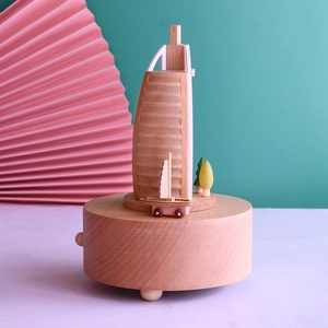 Detail view of wooden Burj Al Arab music box with miniature sailboat on a light wood base