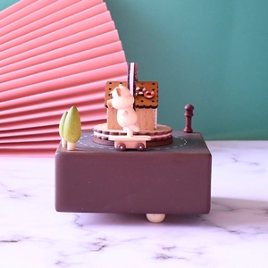 Detailed view of a wooden mechanical music box with rotating pig and gingerbread house