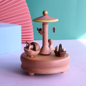 Detail of wooden musical box with rotating animal charms and miniature baby cradle