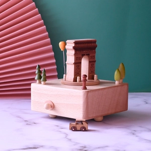 Wooden Arc de Triomphe music box with miniature trees and tiny car on white marble base