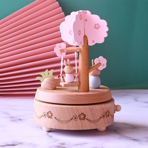 Handcrafted wooden music box featuring cute rabbits on a swing under cherry blossom trees