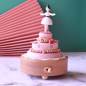 Macro detail of wooden ballerina music box featuring pink cake tiers and dancing girl