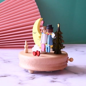 Handcrafted wooden music box featuring romantic moon and star figurines on a natural timber base