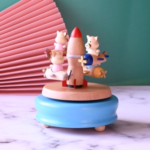 Macro detail of a wooden music box with small pigs on planes circling a central rocket