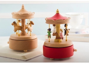 Detailed comparison of natural wood and red carousel music boxes on a cozy desk
