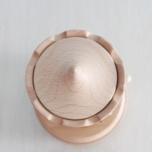 Top view of a minimalist wooden carousel music box with natural grain and a conical top