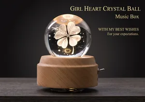 Macro shot of luminous clover crystal ball music box with warm LED wooden base